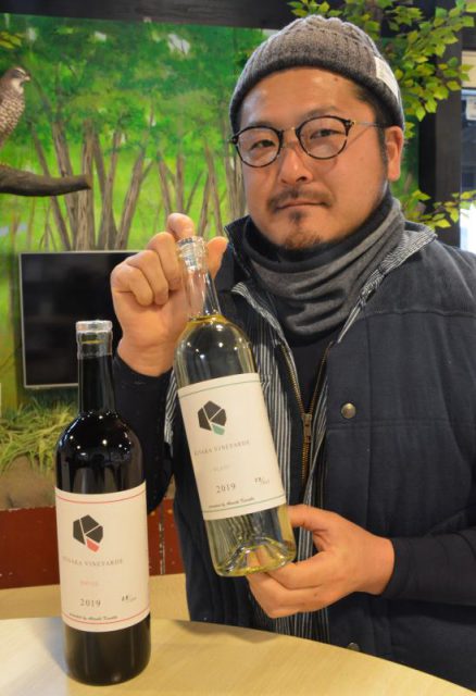 新デザインのラベルを貼った出来たてのワインを持つ日下さん