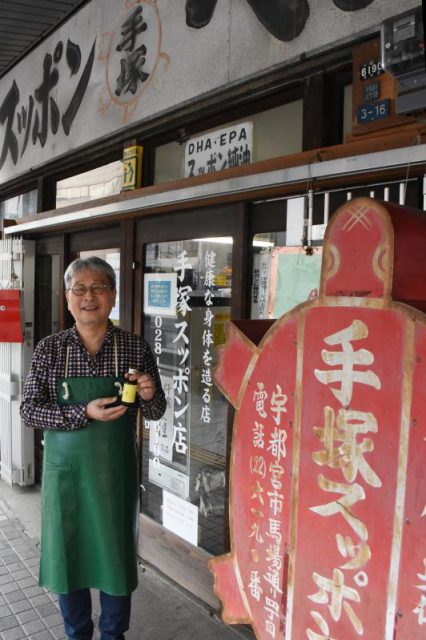 昔ながらの外観を保つ手塚スッポン店。手塚さんが手にしているのがオリジナルドリンク「タオ」