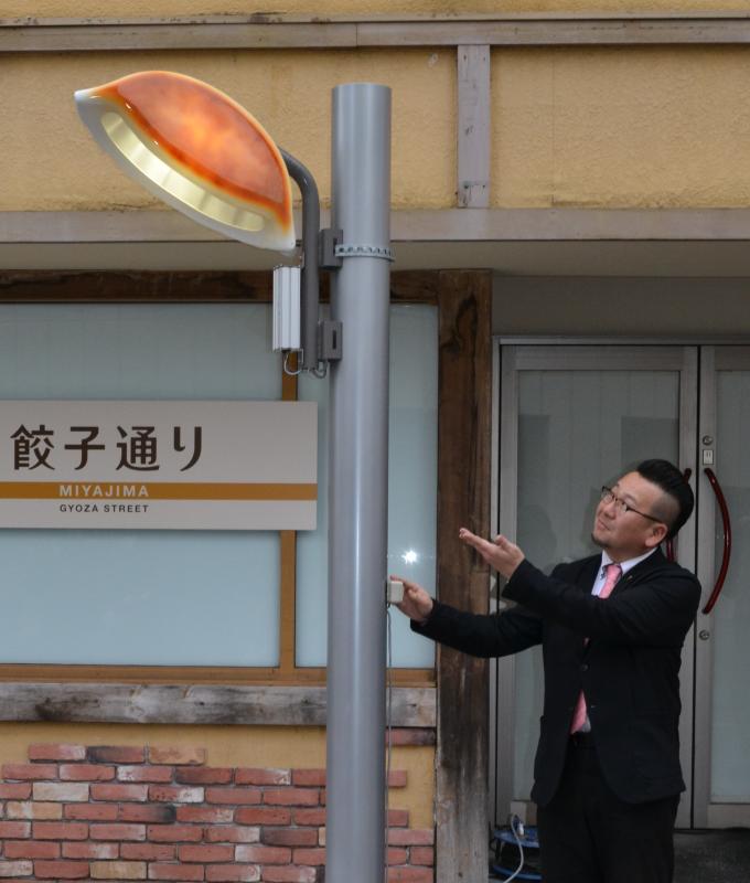 ギョーザ型の街灯を披露する宇都宮餃子会の鈴木章弘事務局長